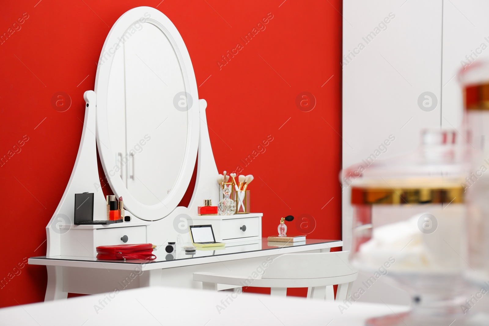 Photo of Elegant dressing room interior with makeup table near red wall