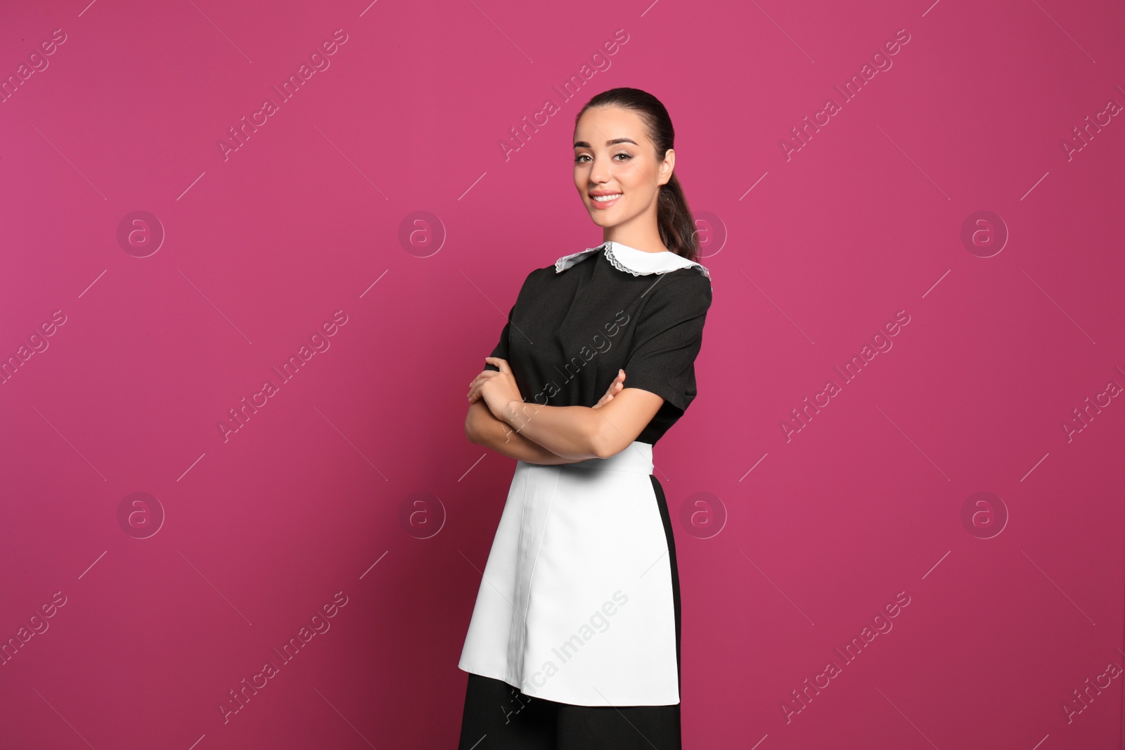 Photo of Portrait of young chambermaid in tidy uniform on color background