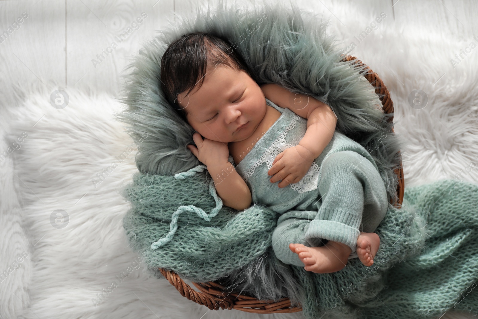 Photo of Cute newborn baby sleeping in wicker basket, top view