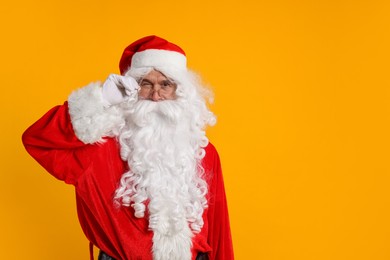 Photo of Merry Christmas. Santa Claus winking on orange background, space for text