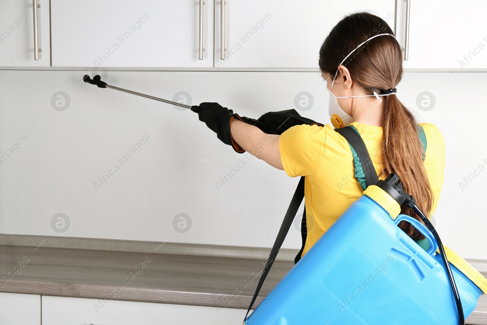 Photo of Pest control worker spraying pesticide in kitchen