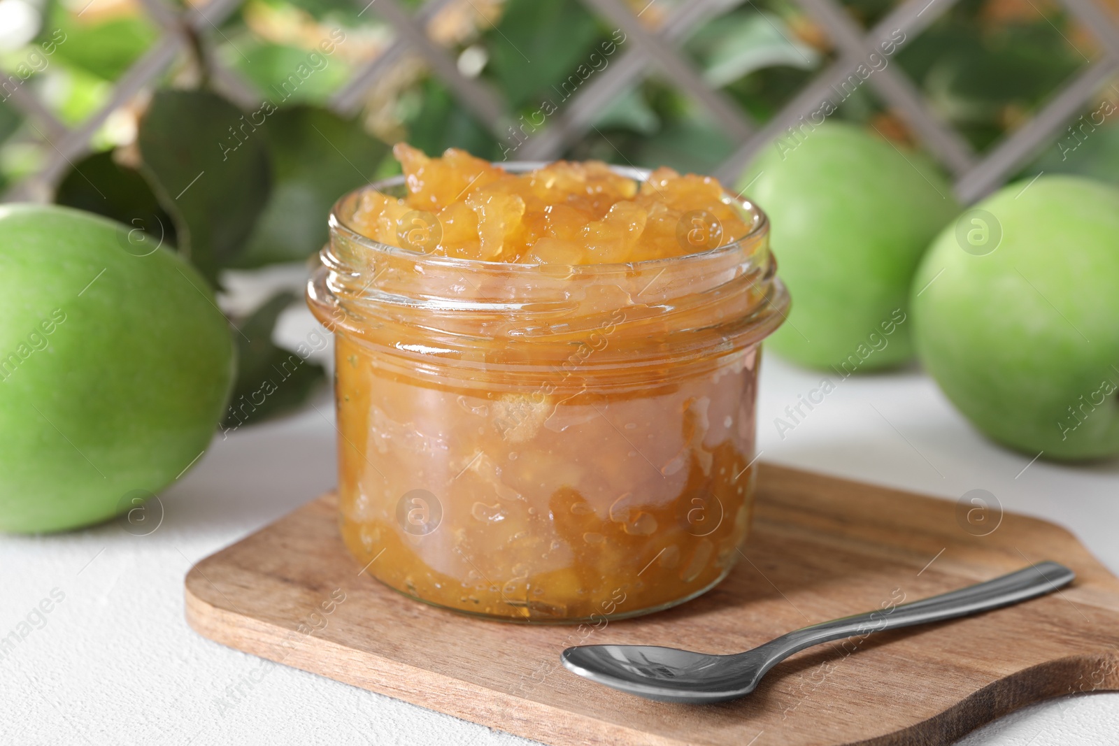 Photo of Glass jar of delicious apple jam and fresh fruits on white table