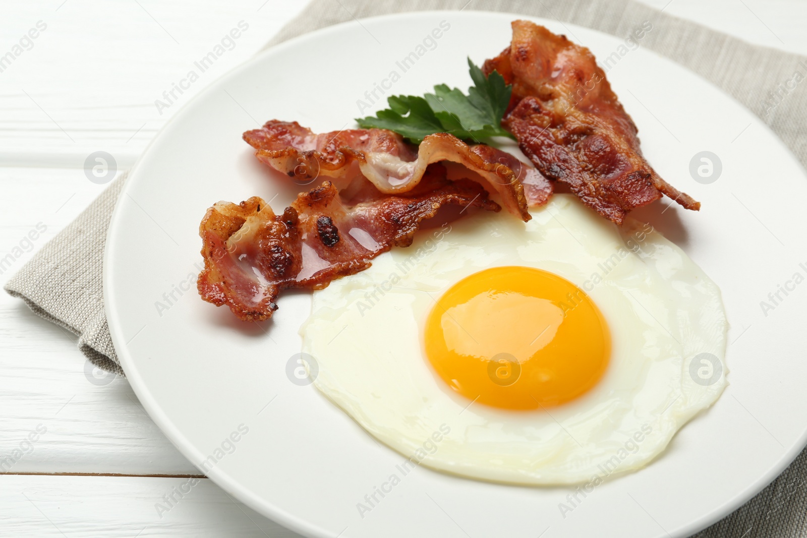 Photo of Delicious breakfast with sunny side up egg on white wooden table, closeup
