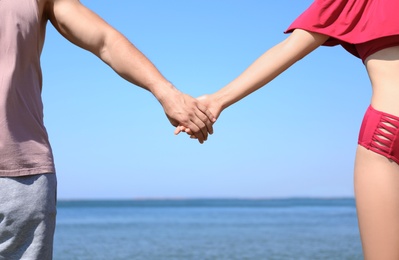 Photo of Happy couple holding hands at beach on sunny day, closeup