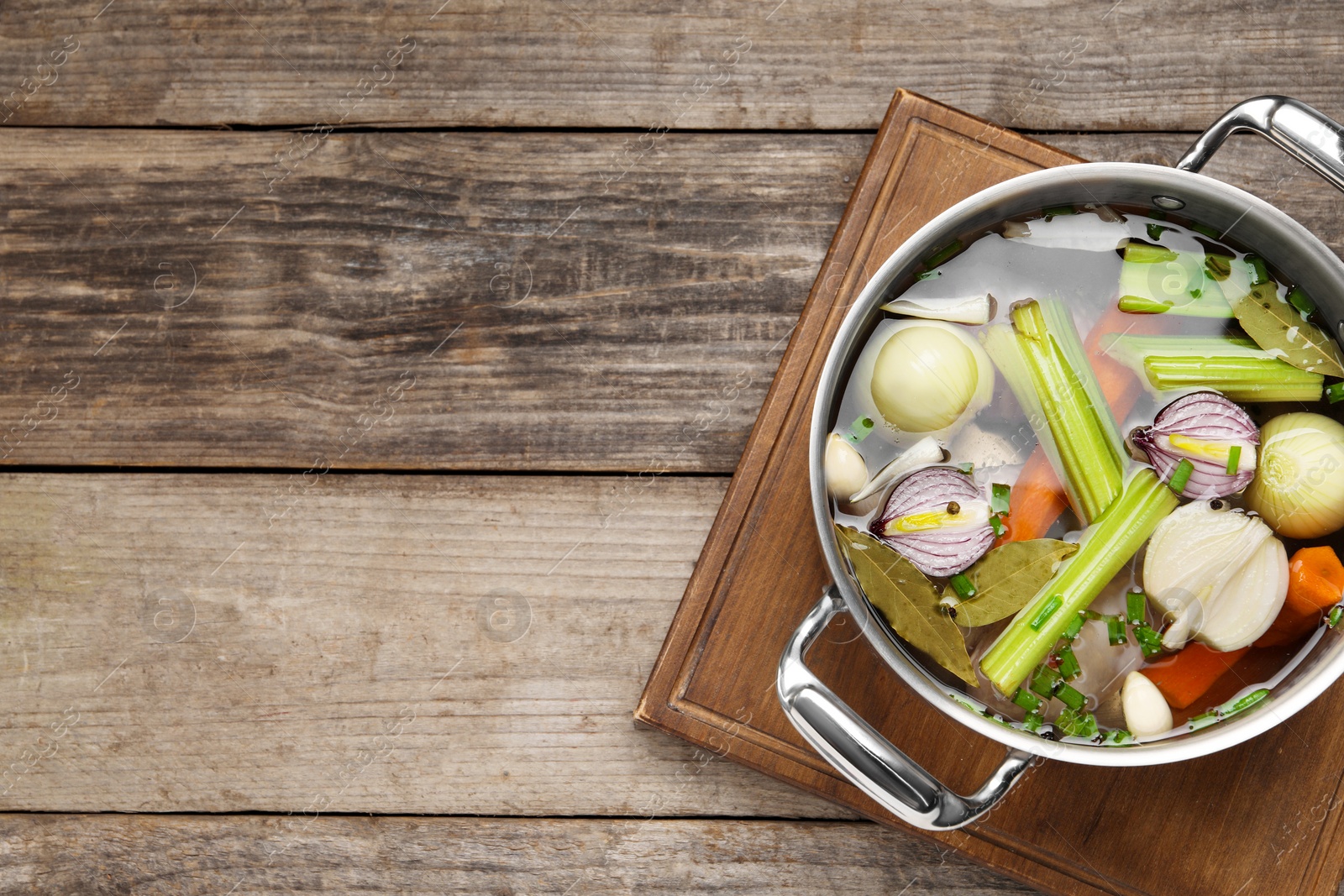 Photo of Different ingredients for cooking tasty bouillon in pot on wooden table, top view. Space for text