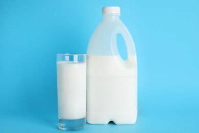Photo of Gallon bottle and glass of milk on light blue background
