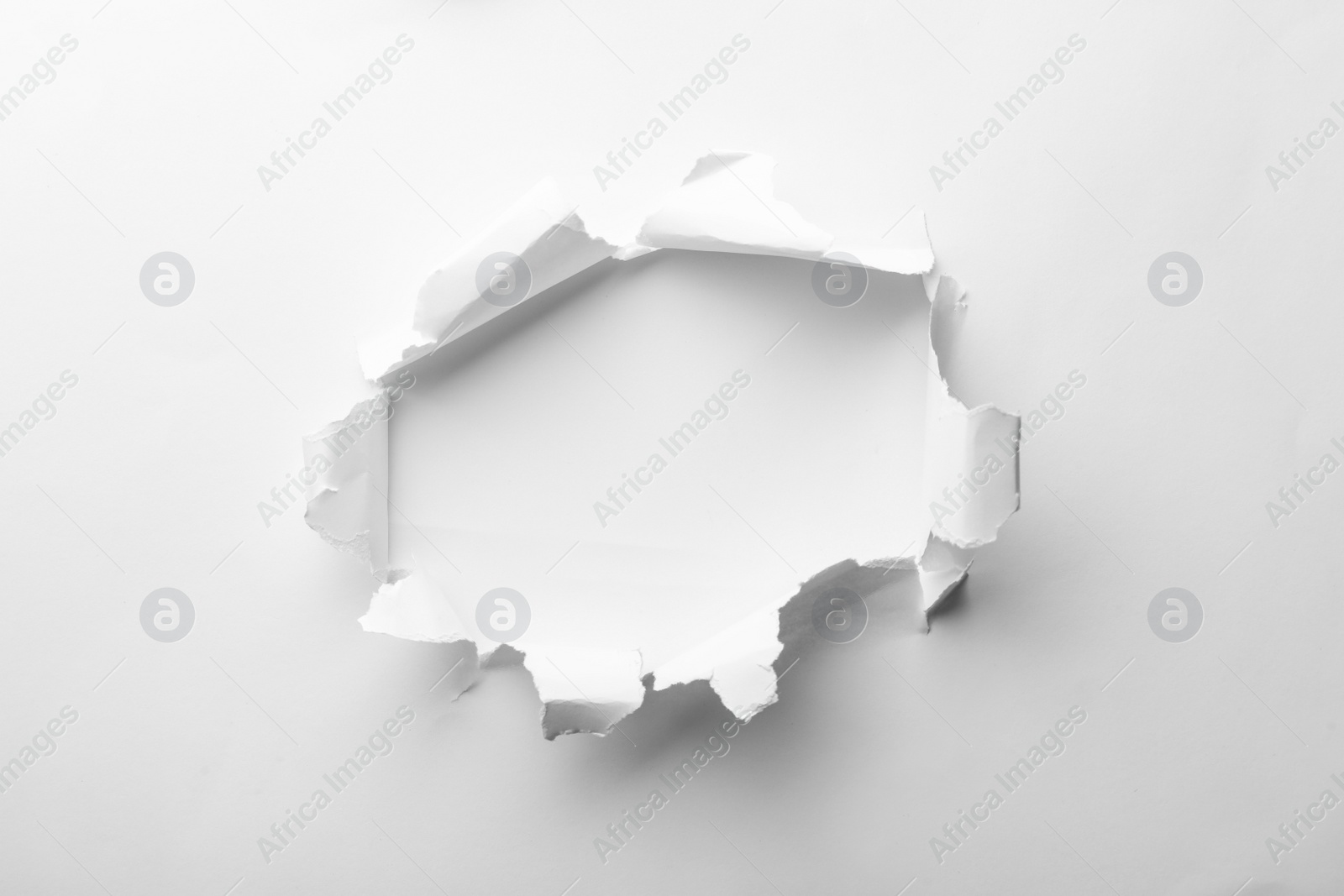 Photo of Hole in white paper on light background