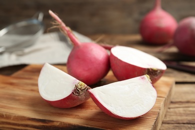 Photo of Cut and whole red turnips on wooden table, closeup