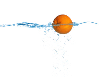 Ripe orange falling down into clear water against white background