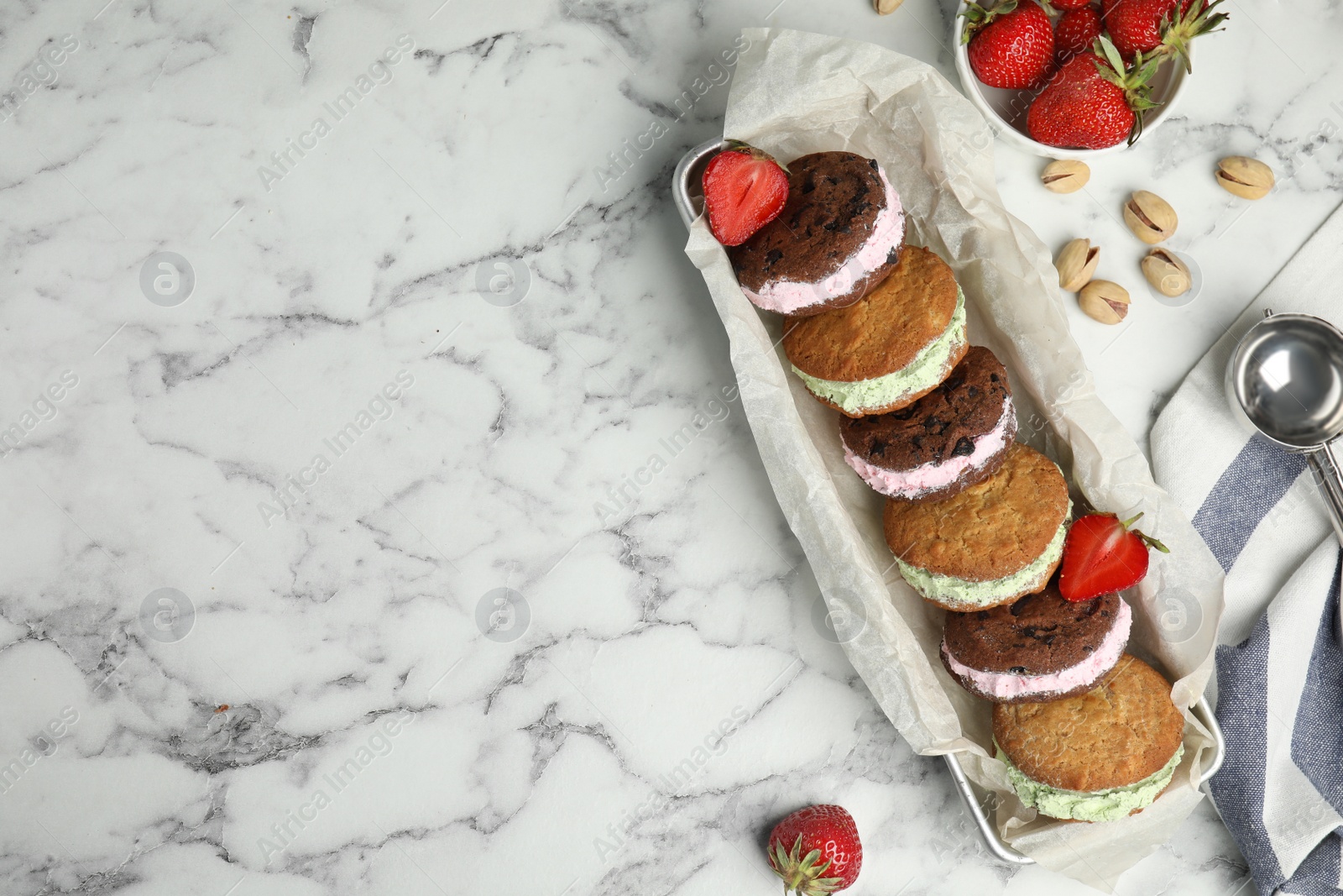 Photo of Different sweet delicious ice cream cookie sandwiches served on table, flat lay. Space for text