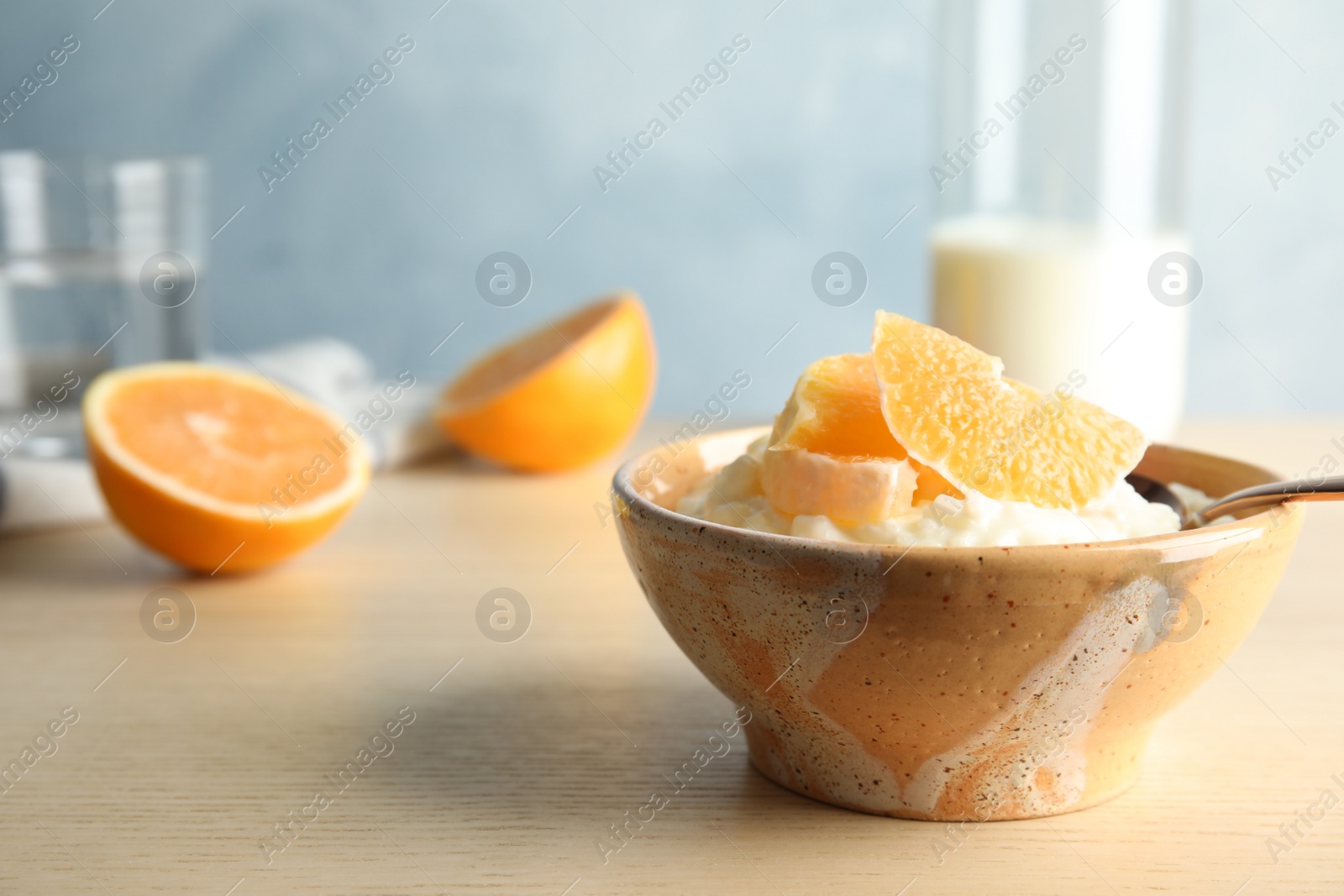 Photo of Creamy rice pudding with orange slices in bowl on wooden table. Space for text