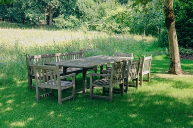 Photo of Empty wooden table with bench and chairs on sunny day outdoors