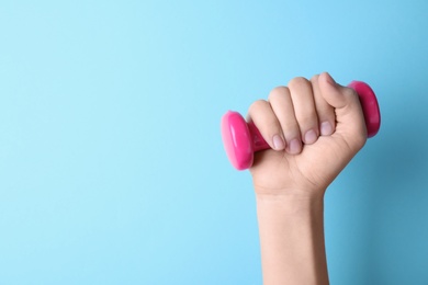 Woman holding vinyl dumbbell on color background, closeup with space for text