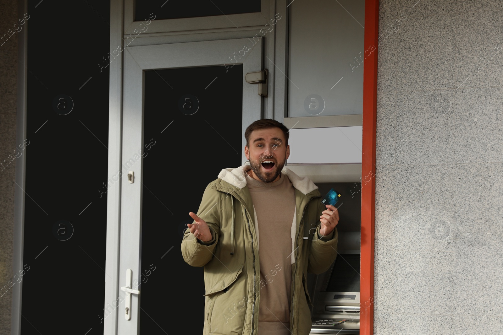 Photo of Happy man with credit card near cash machine outdoors