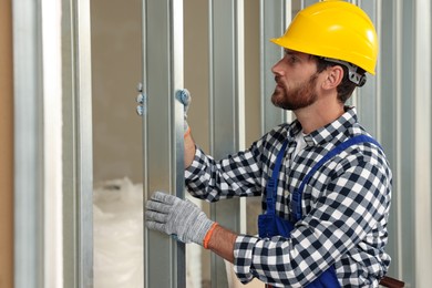 Photo of Professional builder in uniform working with metal bars indoors