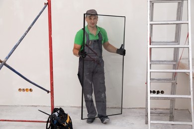 Photo of Worker holding double glazing indoors. Window installation