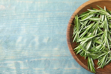 Photo of Wooden bowl with fresh rosemary on color table, flat lay. Space for text