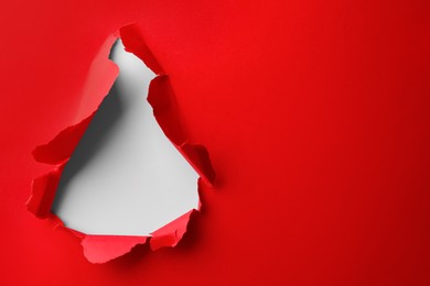 Photo of Hole in red paper on white background, space for text