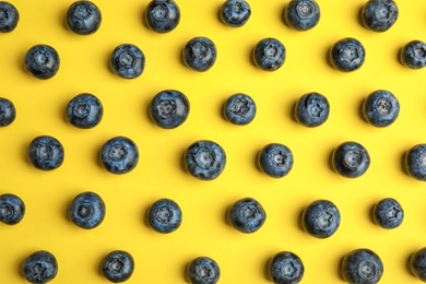 Photo of Tasty ripe blueberries on yellow background, flat lay