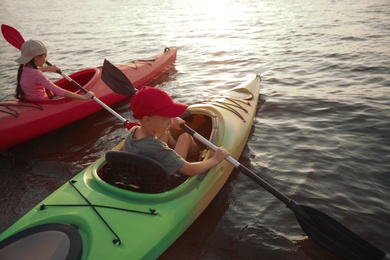 Photo of Children kayaking on river at sunset. Summer camp activity