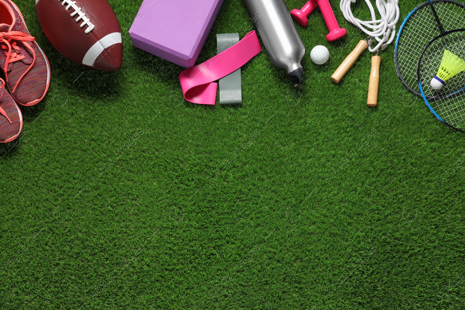 Photo of Different sport tools on green grass, flat lay. Space for text