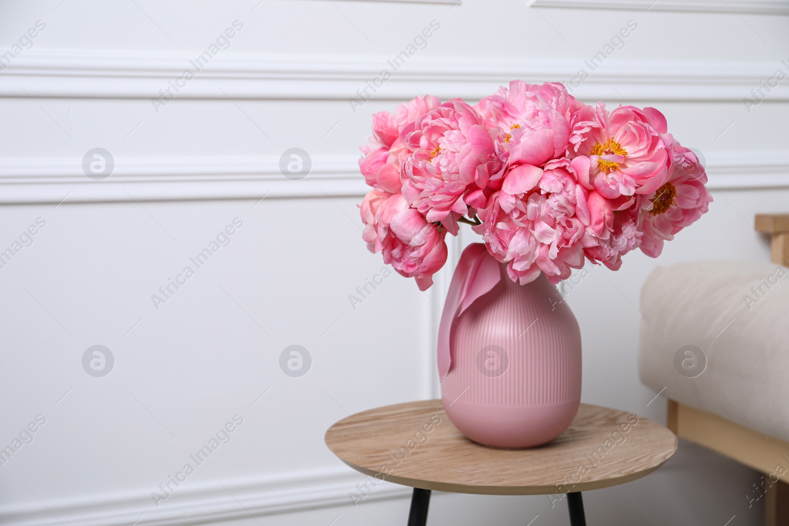 Photo of Beautiful bouquet of pink peonies in vase on wooden table indoors. Space for text