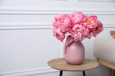 Beautiful bouquet of pink peonies in vase on wooden table indoors. Space for text