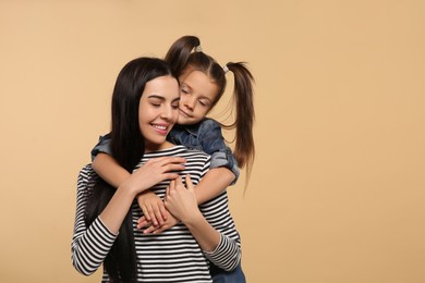 Happy woman with her daughter on beige background, space for text. Mother's day celebration