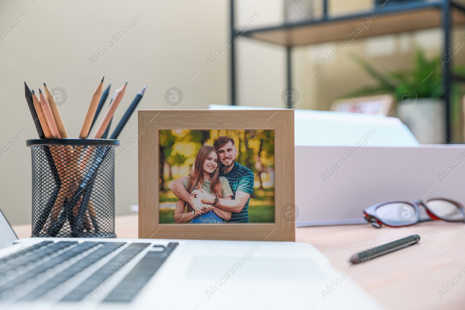 Photo of Framed photo of happy couple near laptop on wooden table in office