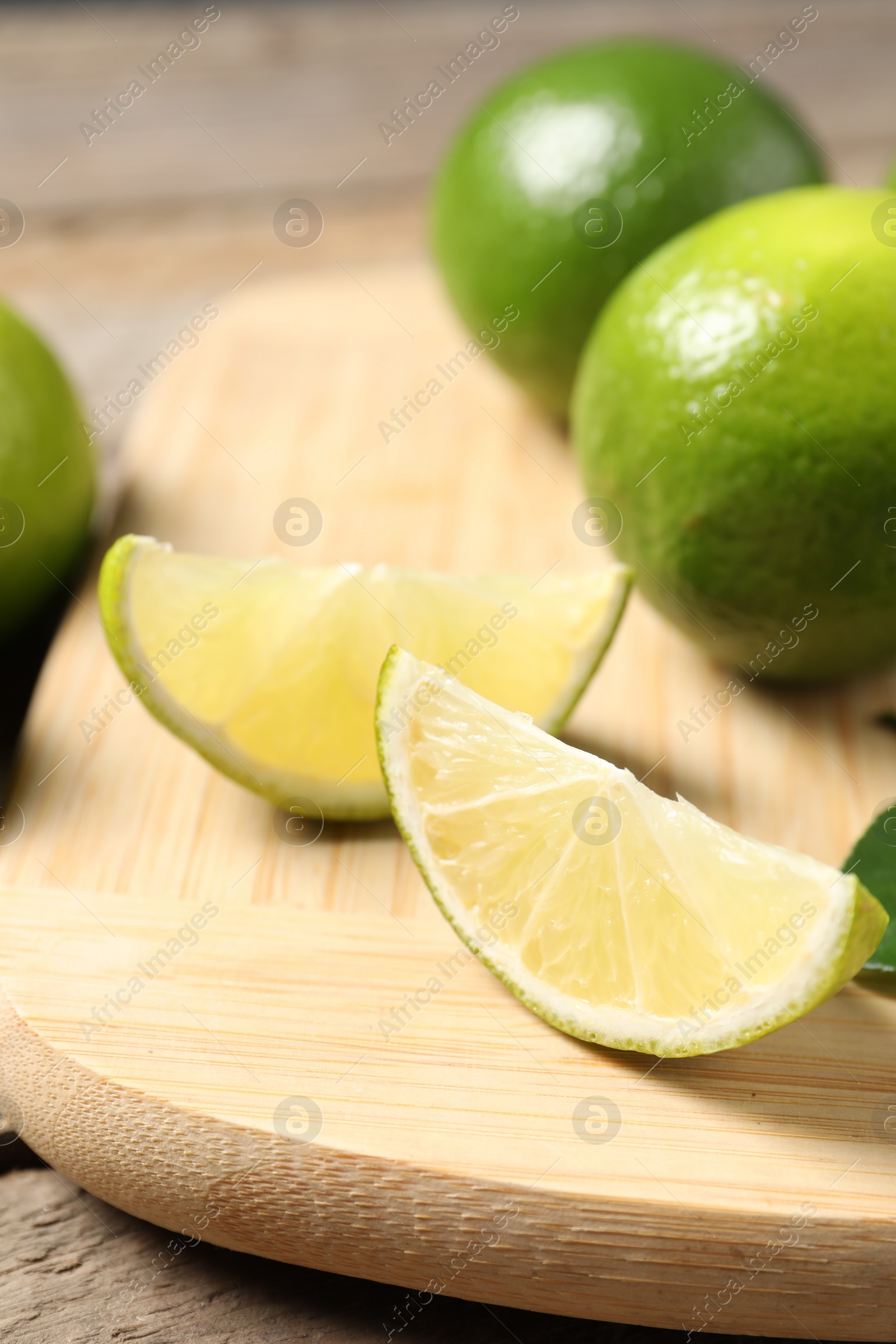 Photo of Whole and cut fresh limes on table, closeup