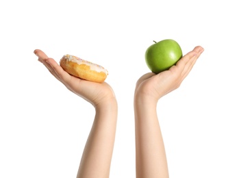 Photo of Concept of choice. Woman holding apple and doughnut on white background, closeup