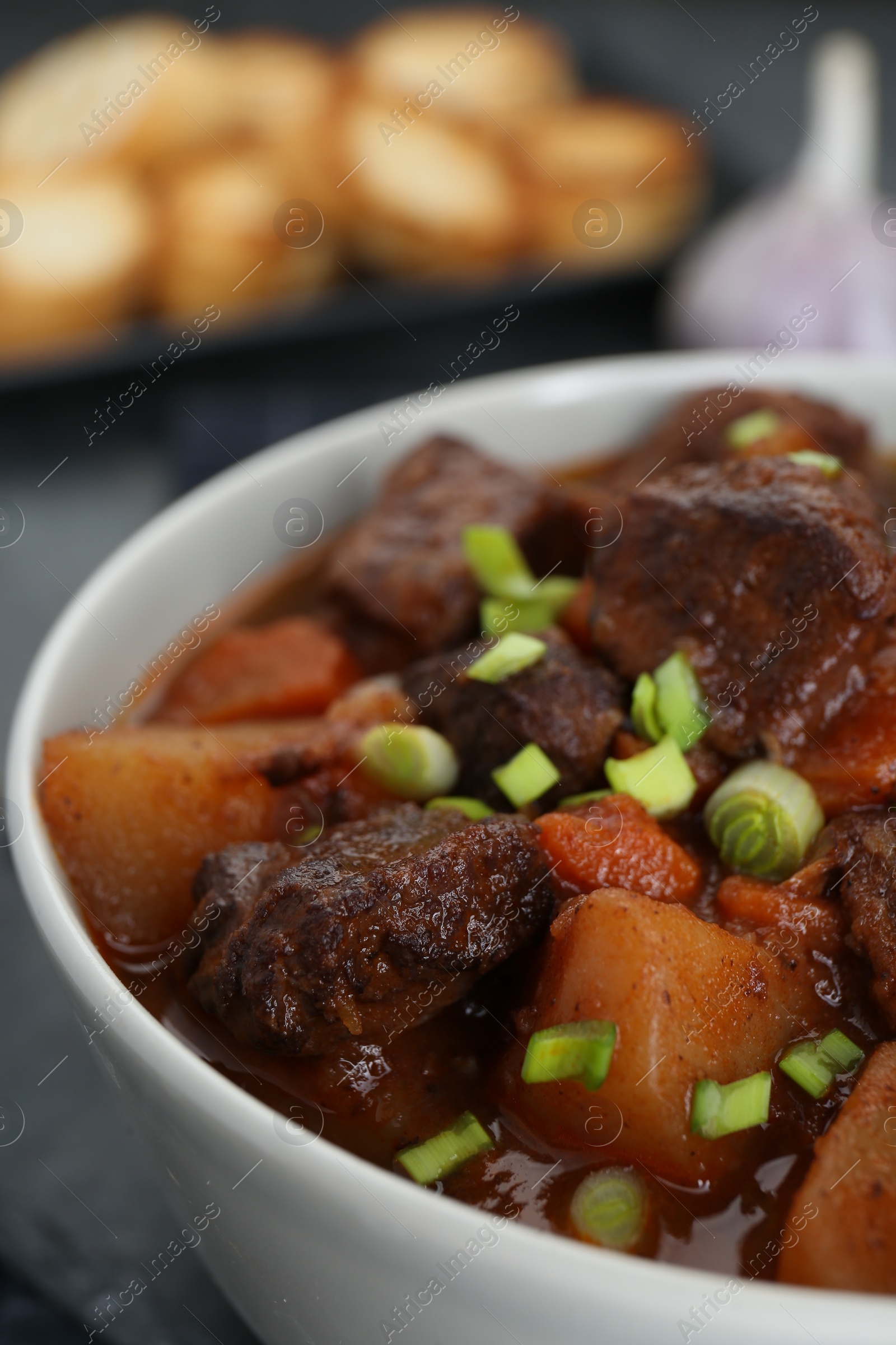 Photo of Delicious beef stew with carrots, green onions and potatoes, closeup