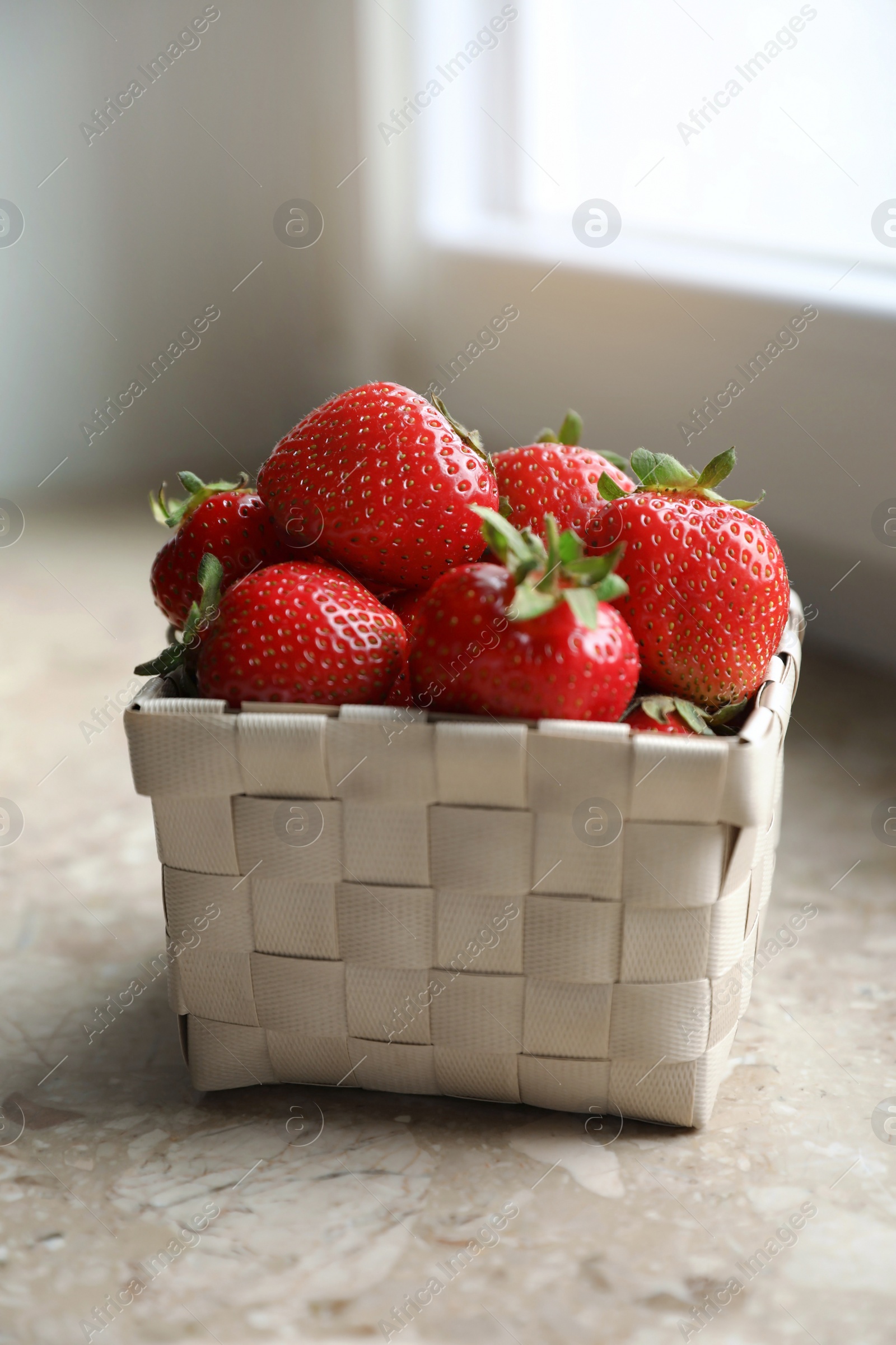 Photo of Fresh juicy strawberries in wicker basket on windowsill, closeup