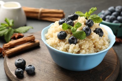 Photo of Tasty quinoa porridge with blueberries and mint in bowl on table, closeup