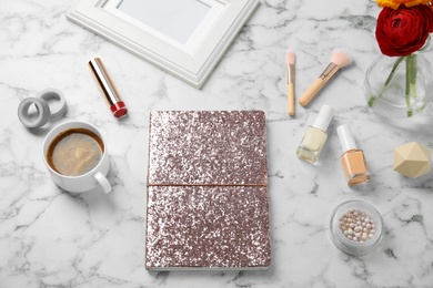 Photo of Composition with notebook, coffee and cosmetics on marble table, above view
