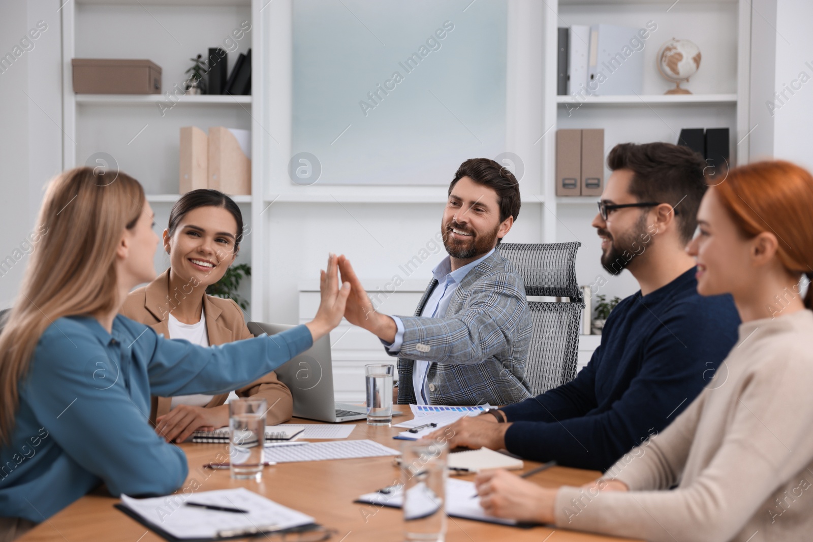 Photo of Team of employees joining hands in office