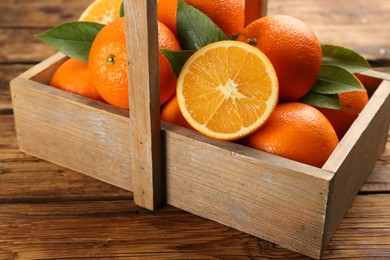 Photo of Delicious ripe oranges in basket on wooden table