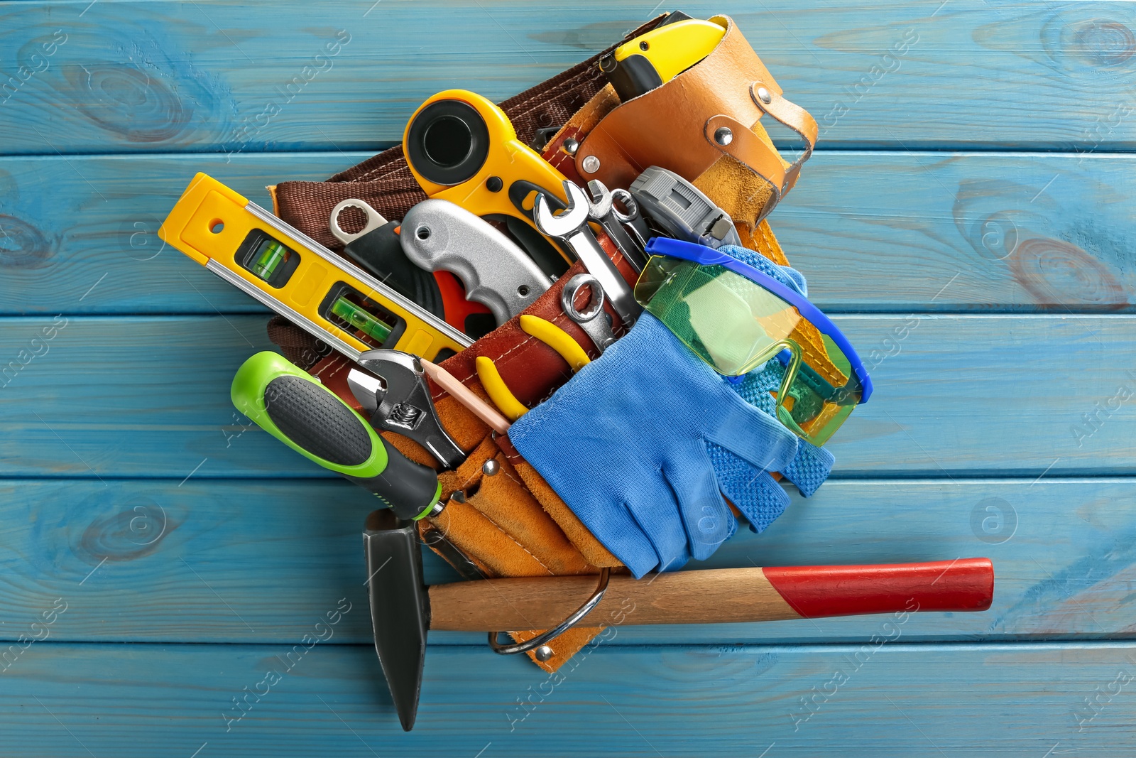 Photo of Belt with different tools on light blue wooden table, top view