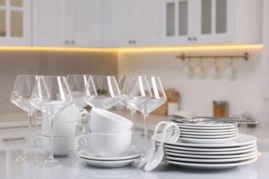 Photo of Set of clean dishware, glasses and cutlery on table in kitchen