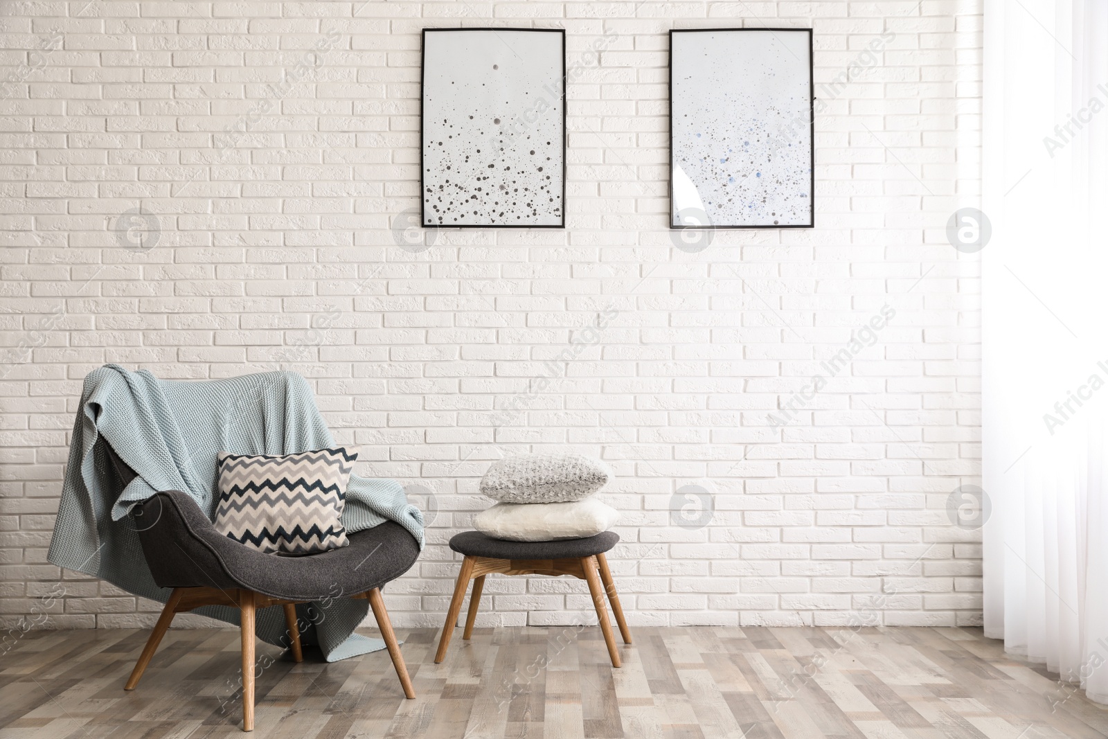 Photo of Stylish interior with plaid, pillows and armchair near brick wall, space for text