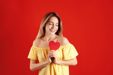 Portrait of woman with paper heart on color background