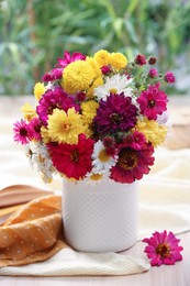 Photo of Vase with beautiful bouquet, open book and cloth on wooden table