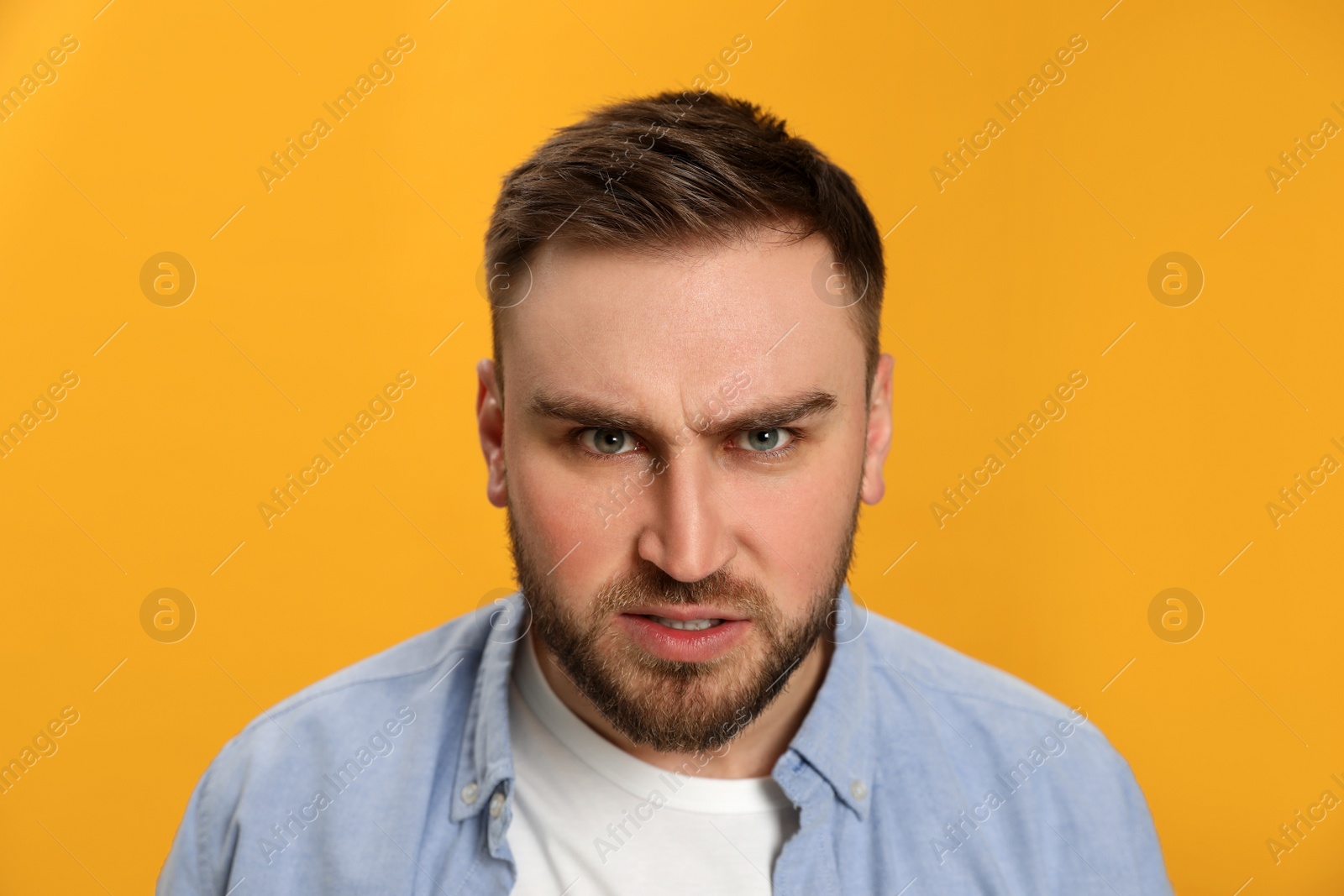 Photo of Angry young man on yellow background. Hate concept