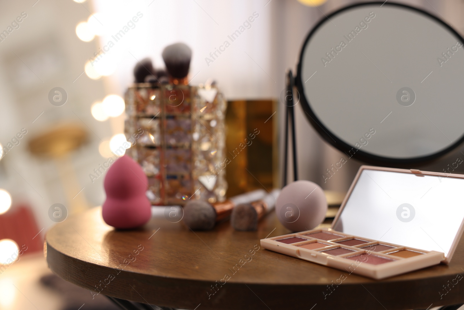 Photo of Different beauty products and mirror on wooden table in makeup room, closeup