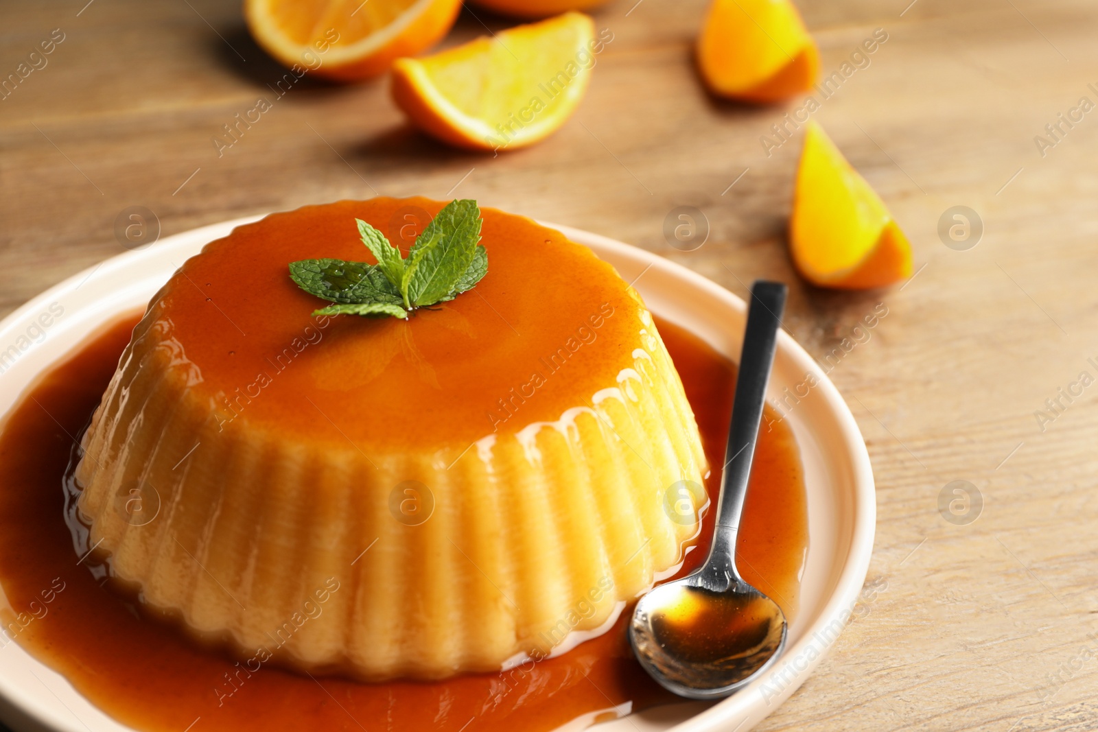 Photo of Delicious pudding with caramel and mint on wooden table, closeup