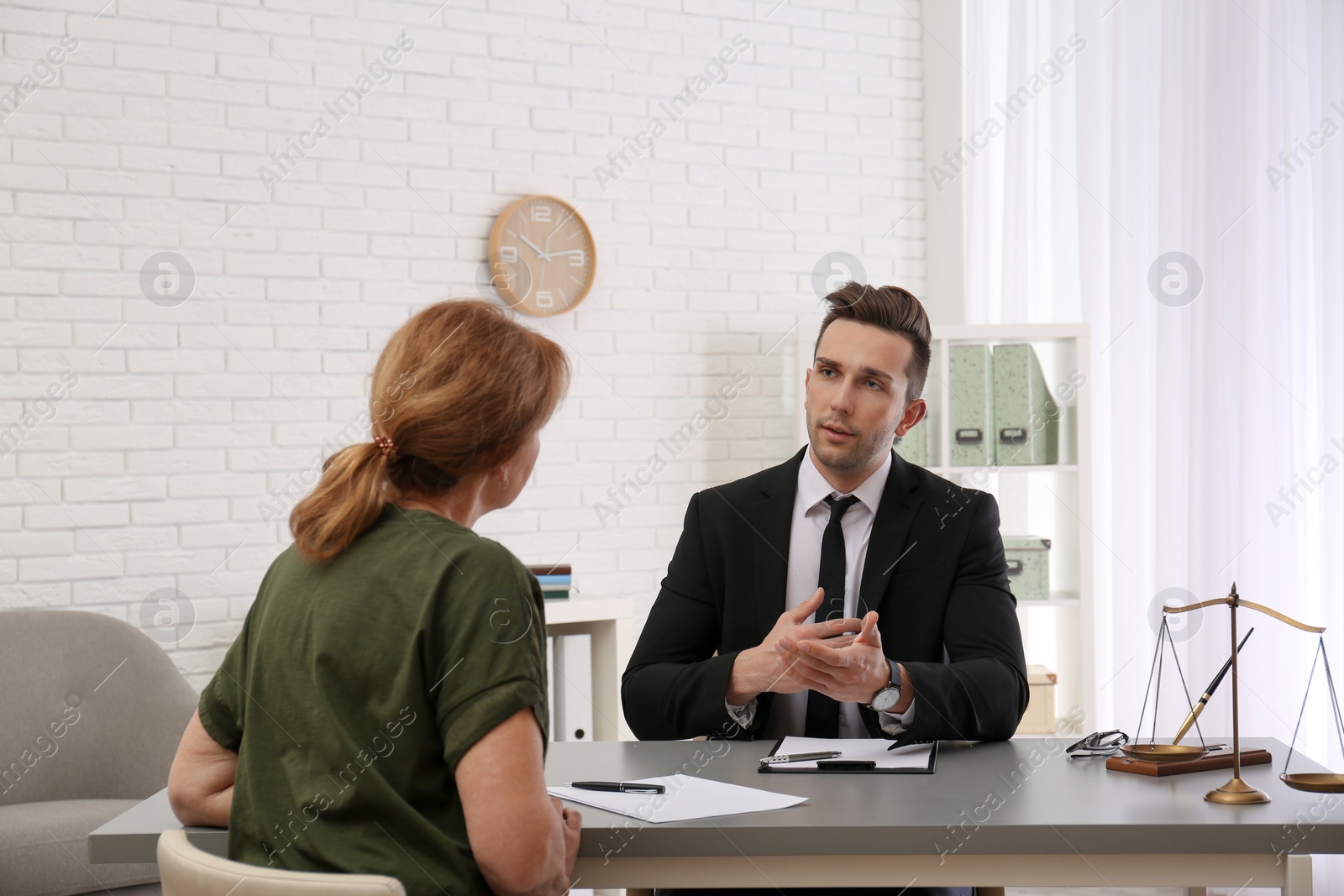 Photo of Young lawyer having meeting with senior client in office