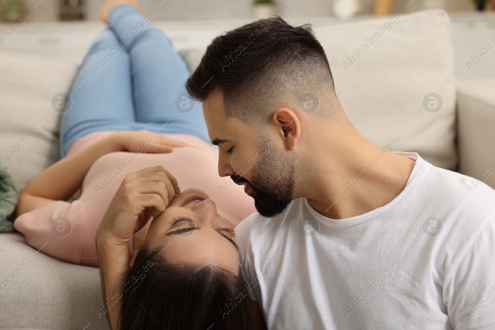 Photo of Affectionate young couple spending time together on sofa indoors