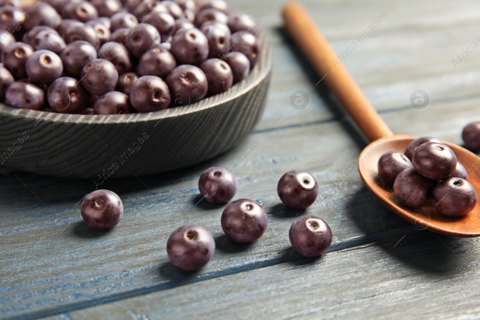 Photo of Plate and spoon with fresh acai berries on wooden table