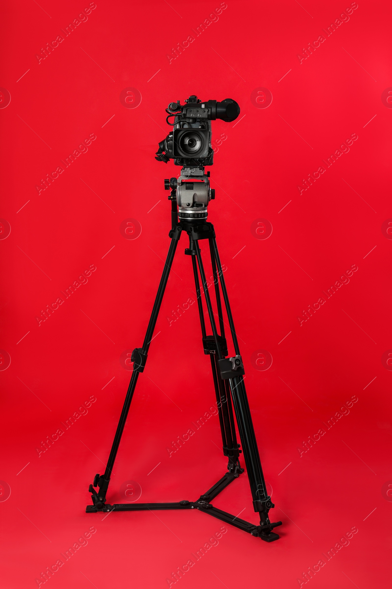 Photo of Modern professional video camera on red background