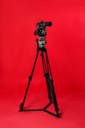 Modern professional video camera on red background